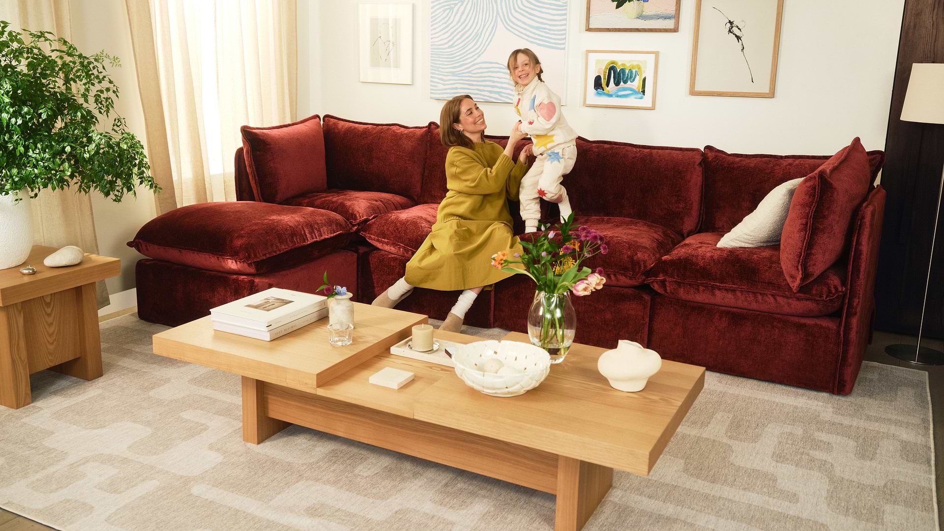 Couple sitting on white sectional reading and working on a laptop.