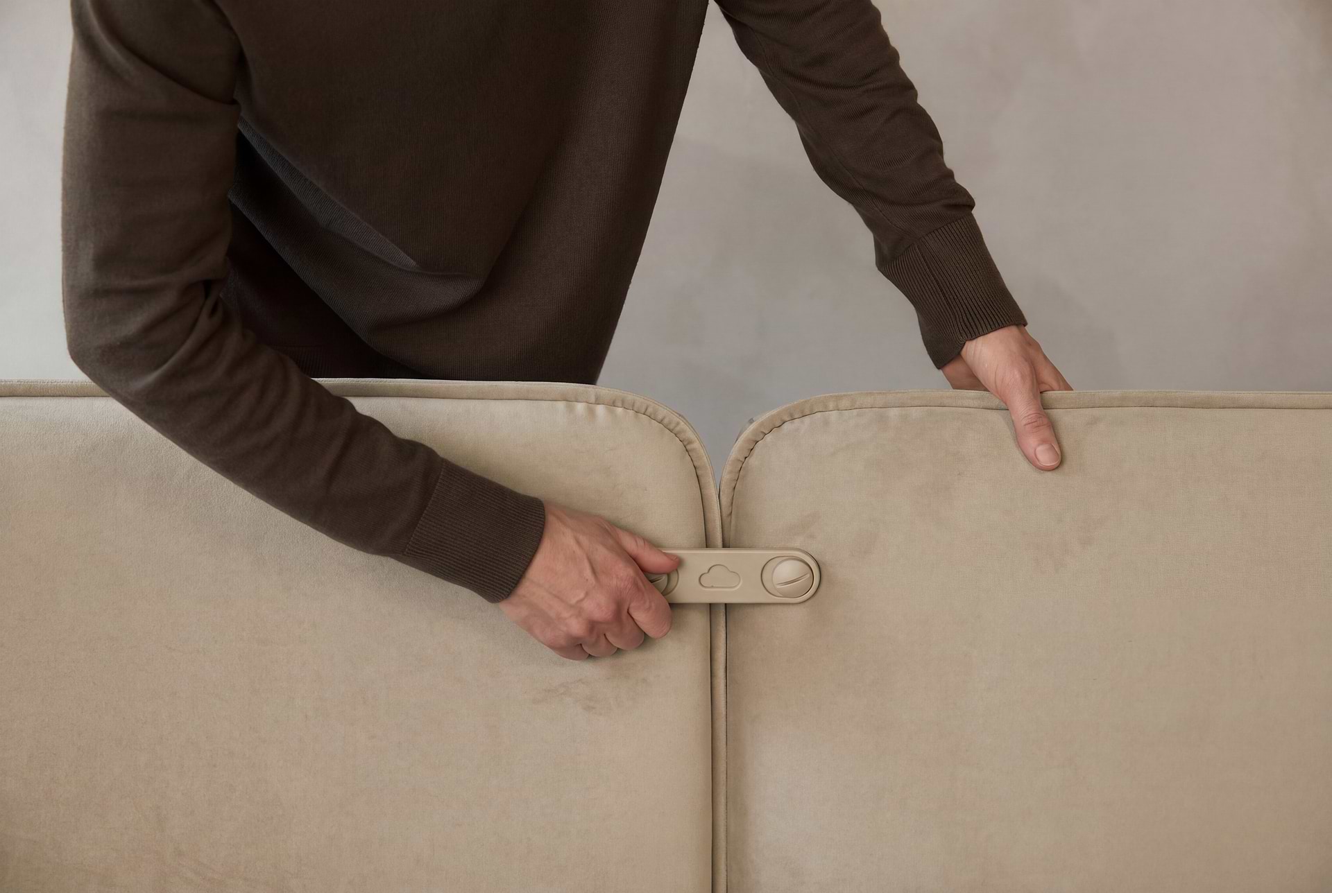 Person fastening together two back modules for a sofa with their hands.