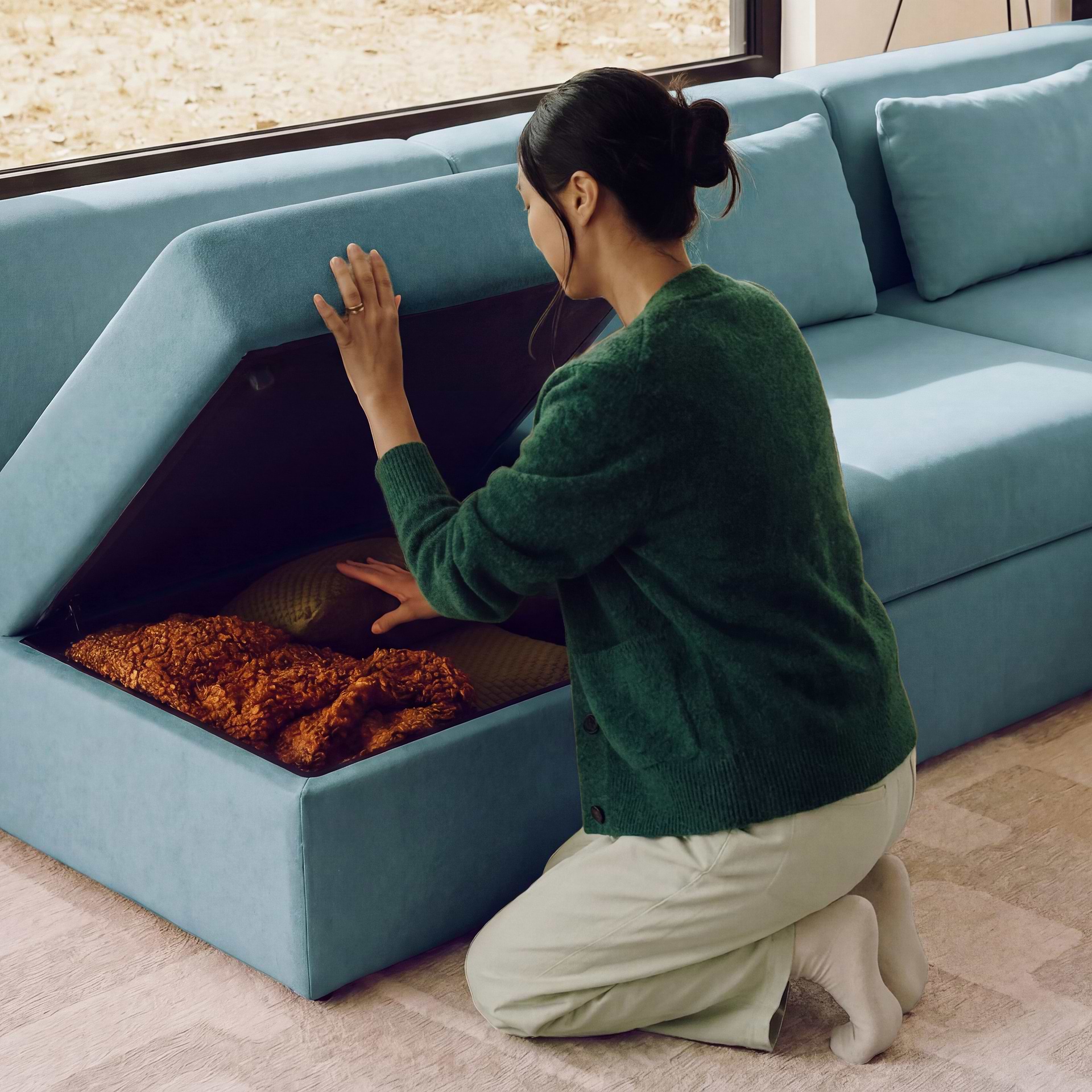 Woman stores book inside grey storage ottoman.