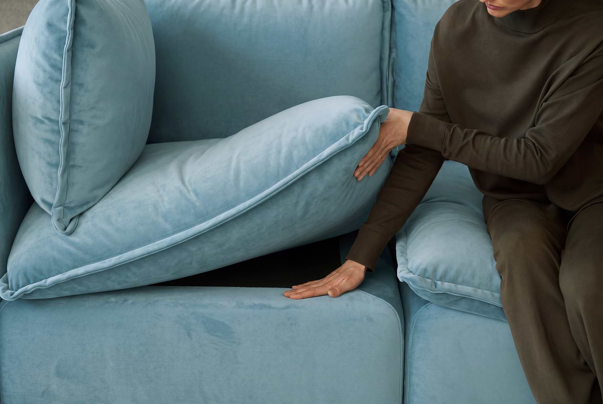 Person lifting up the sofa cushion to reveal padded base underneath.